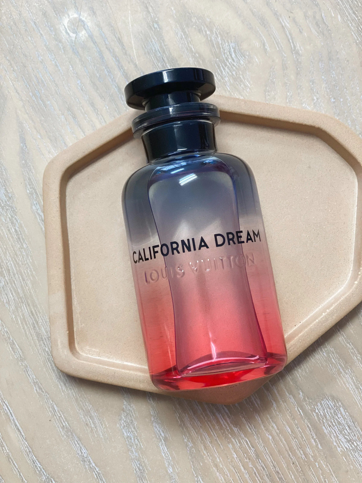 Louis Vuitton California Dream perfume bottle glowing in golden-hour light on a marble tray.