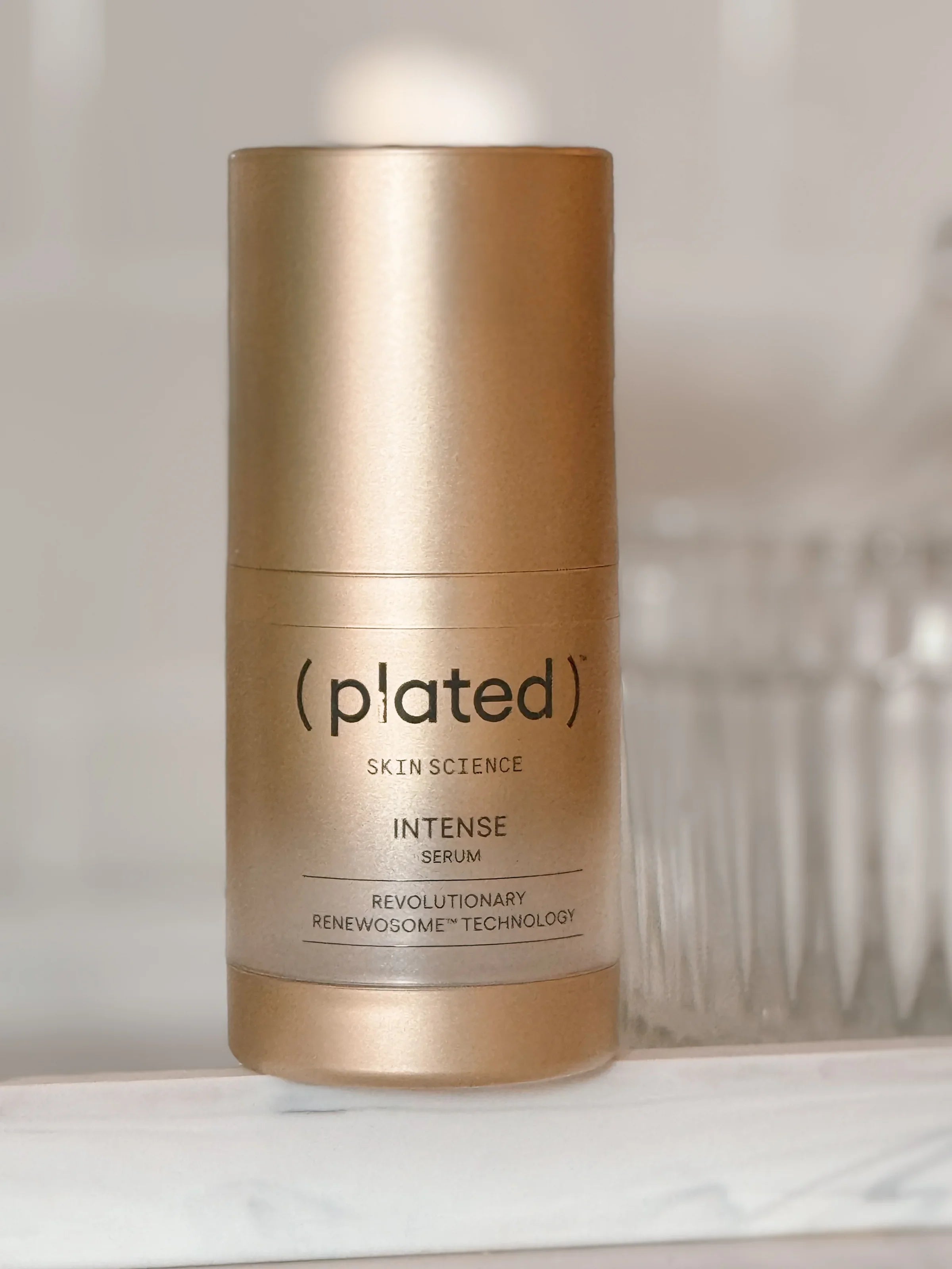 gold plated intense exosomes serum on a marble tray. crystal dish is in the background.