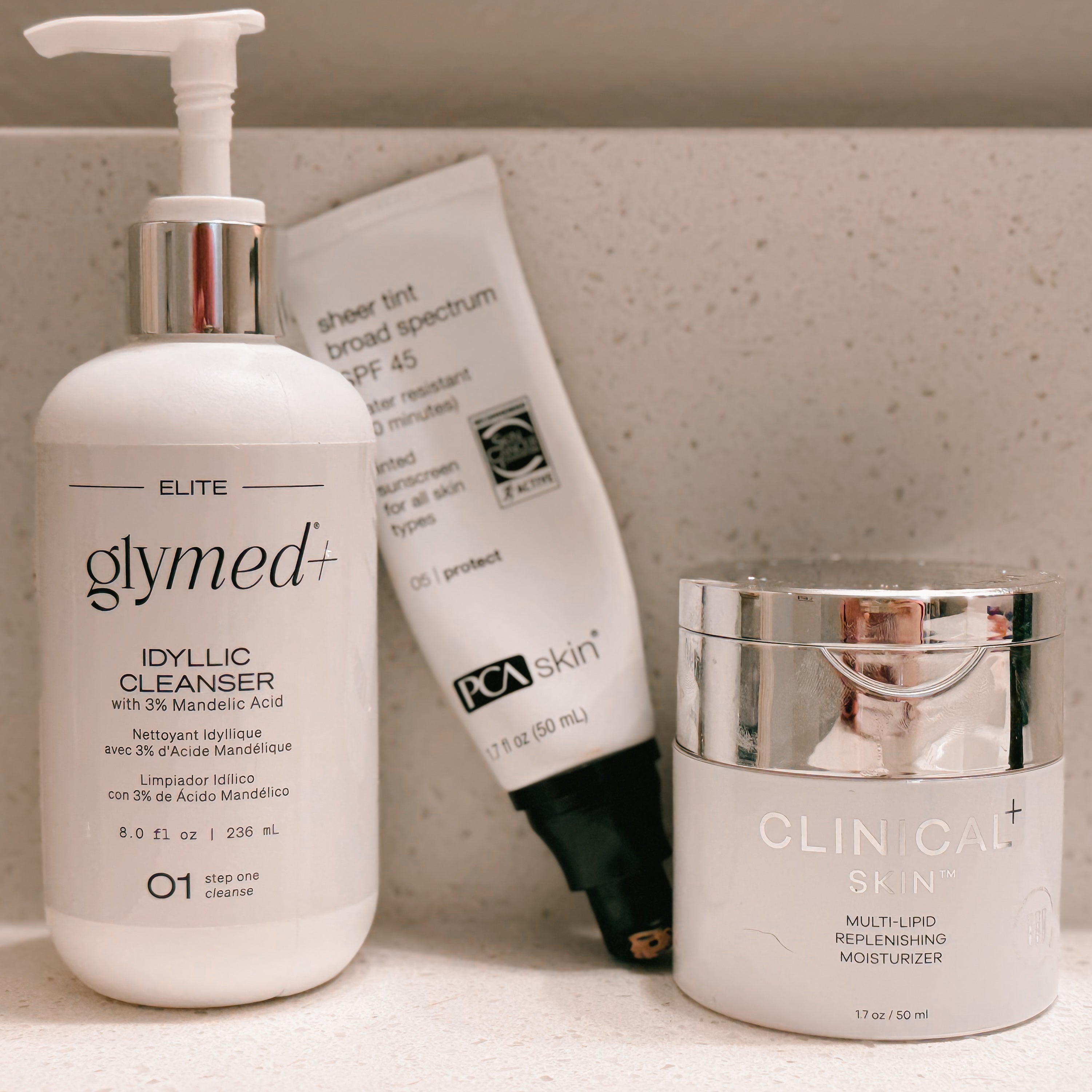 three skincare products on a mable shelf. glymed idyllic cleanser, pca tinted spf, clinical skin moisturizer