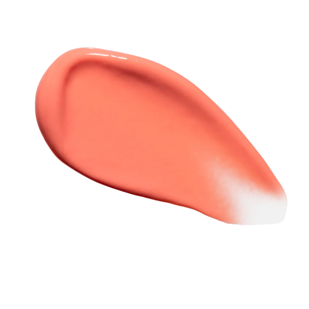 Smeared coral-colored lip gloss product on a white background