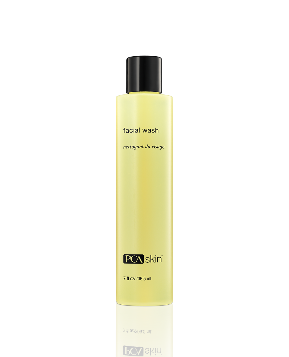 Yellow facial wash bottle with black cap on a white background