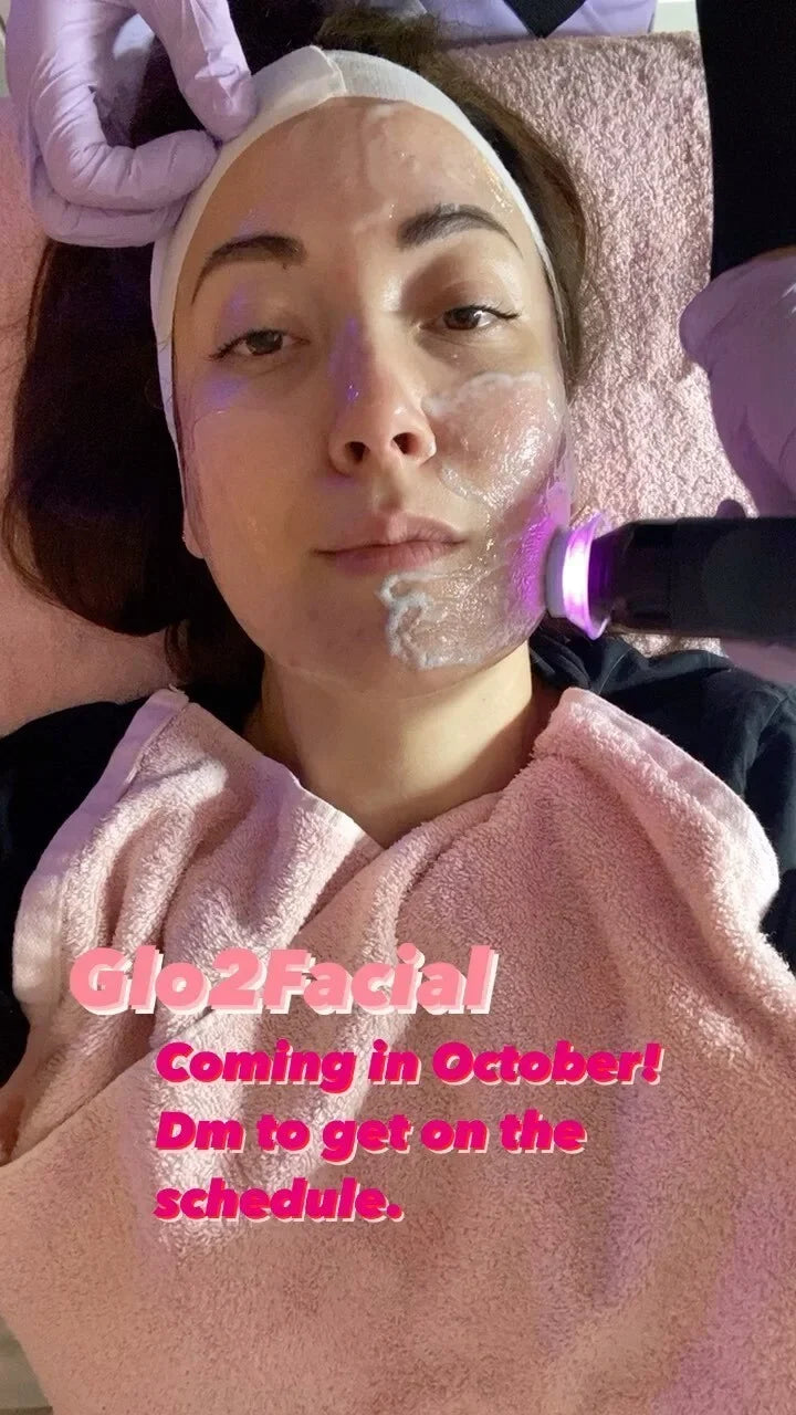 woman receiving a glo2facial with pink towels and pink glowing handpiece.