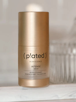 gold plated intense exosomes serum on a marble tray.  crystal dish is in the background.