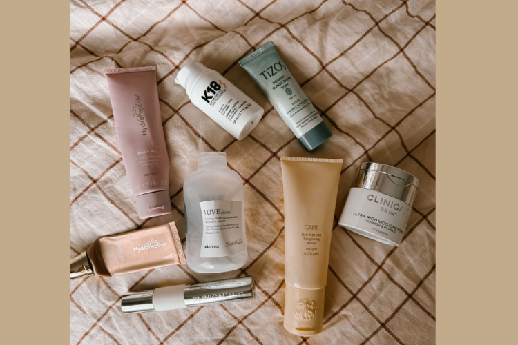 self-care empties on a towel.  ft. k18, oribe, clincal skin, tizo and hydropeptide reviews