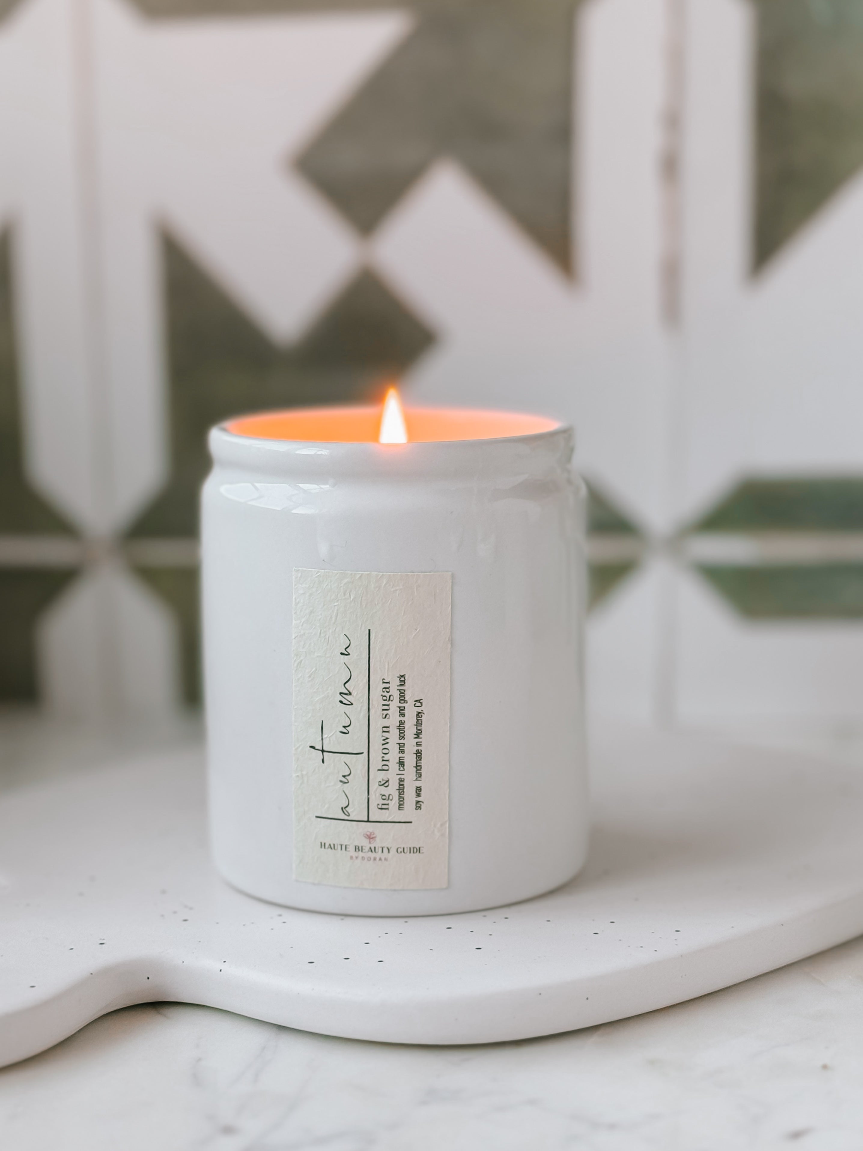 Autumn Candle in a white jar with a label on a marble surface