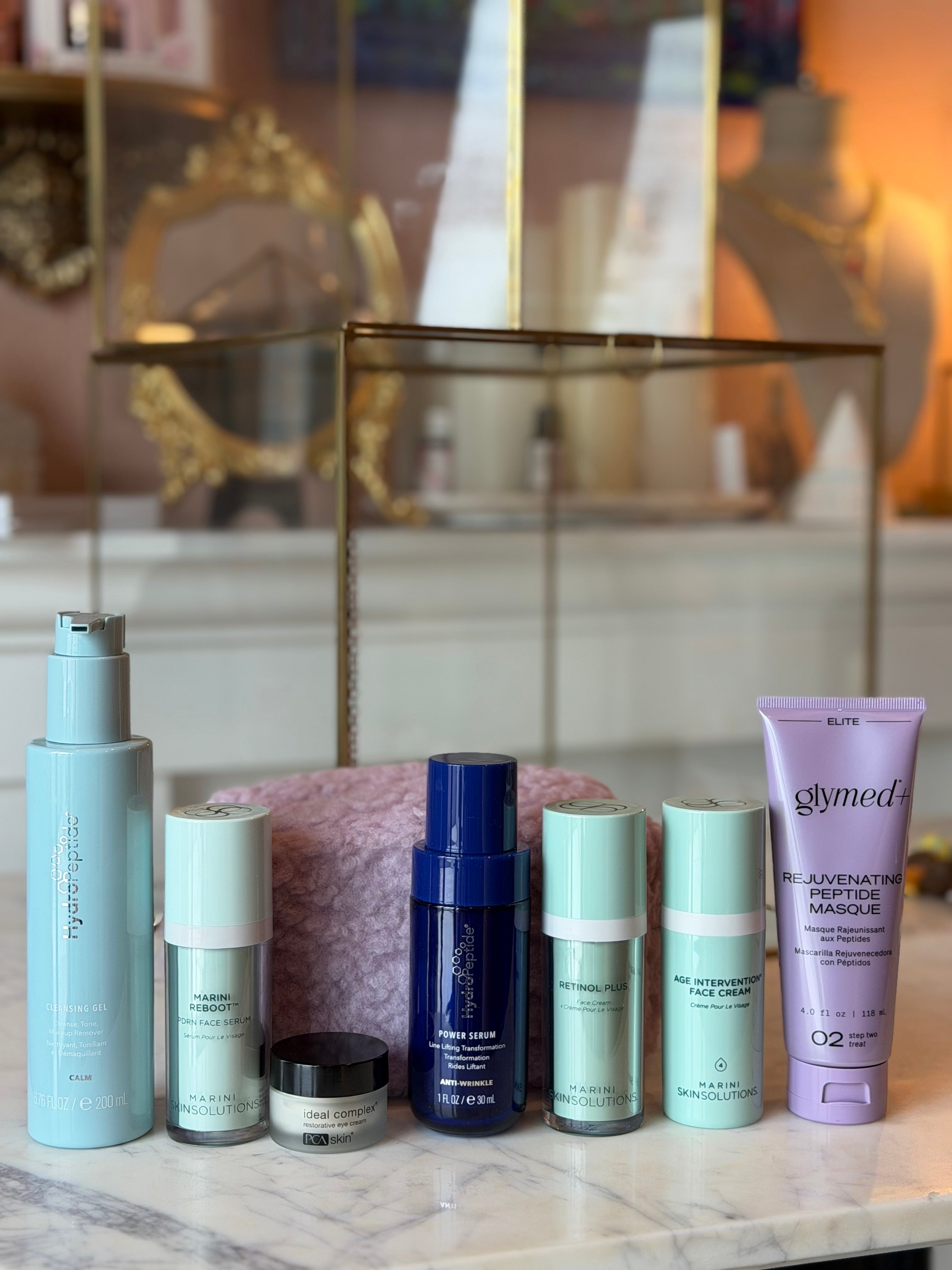 Collection of skincare products on a marble surface with decorative background