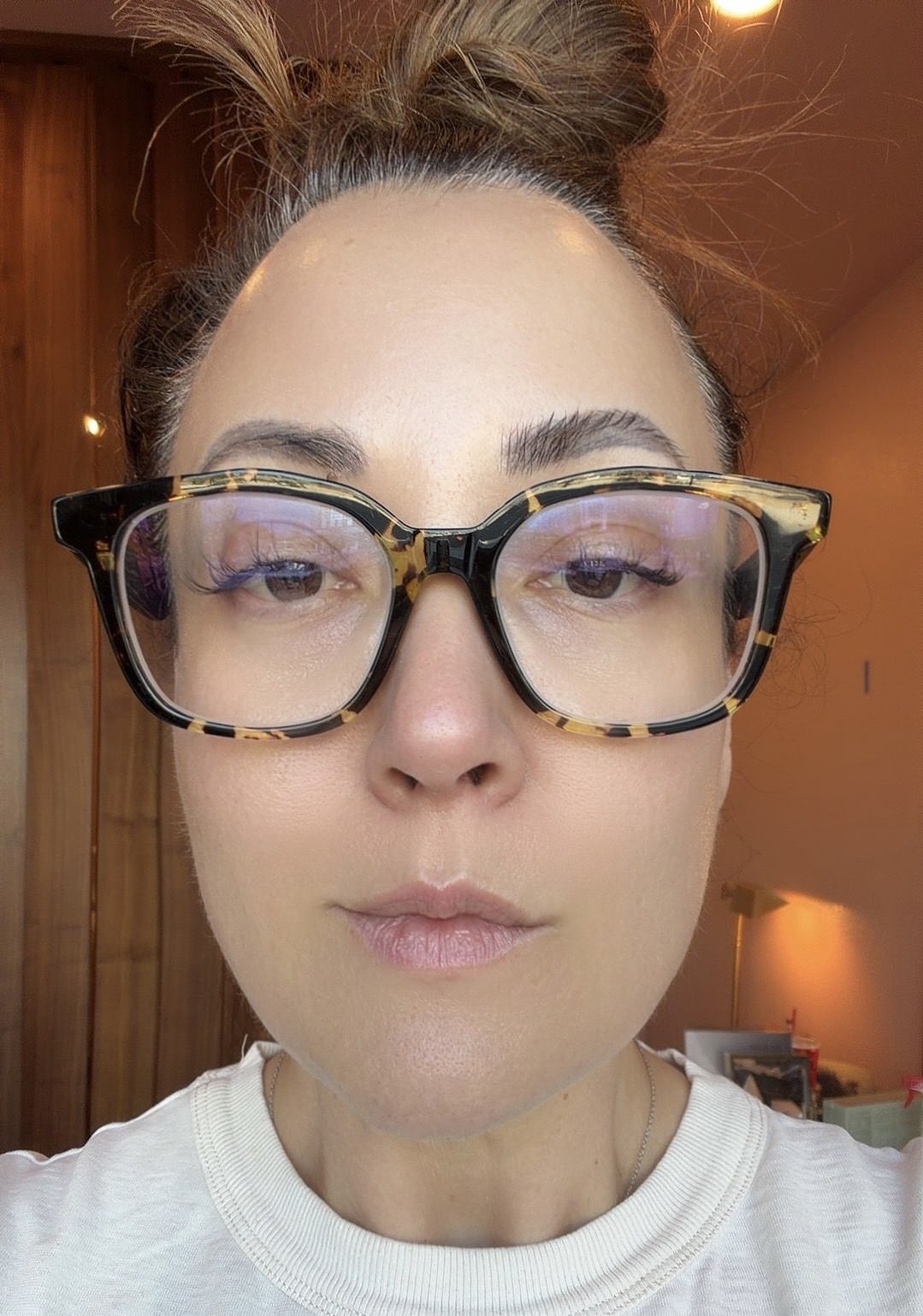 Person wearing glasses with a blurred background with soap brows using brow laminate