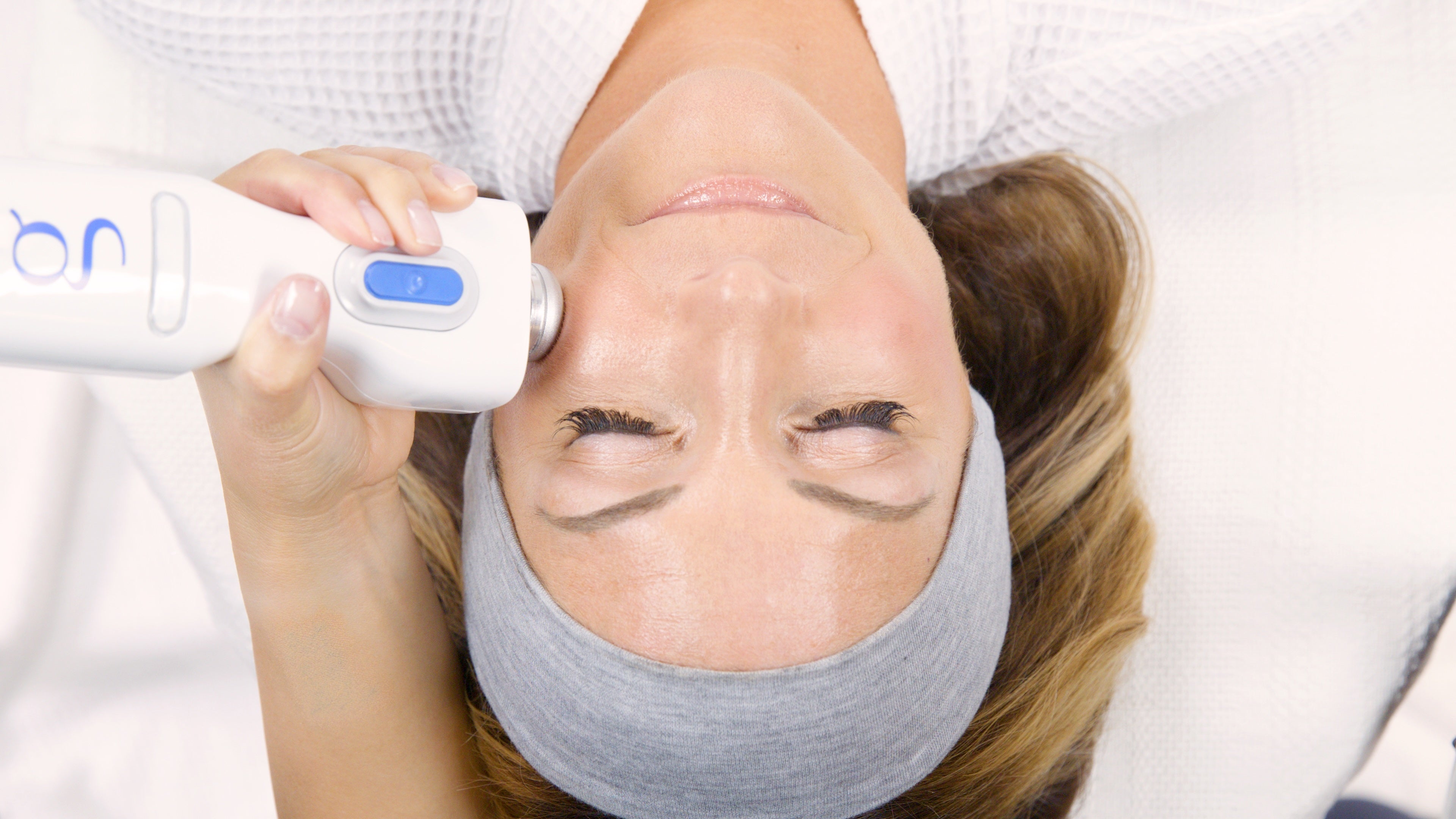 Woman receiving a Gacial skin treatment with a device Glacial handpiec on her face.