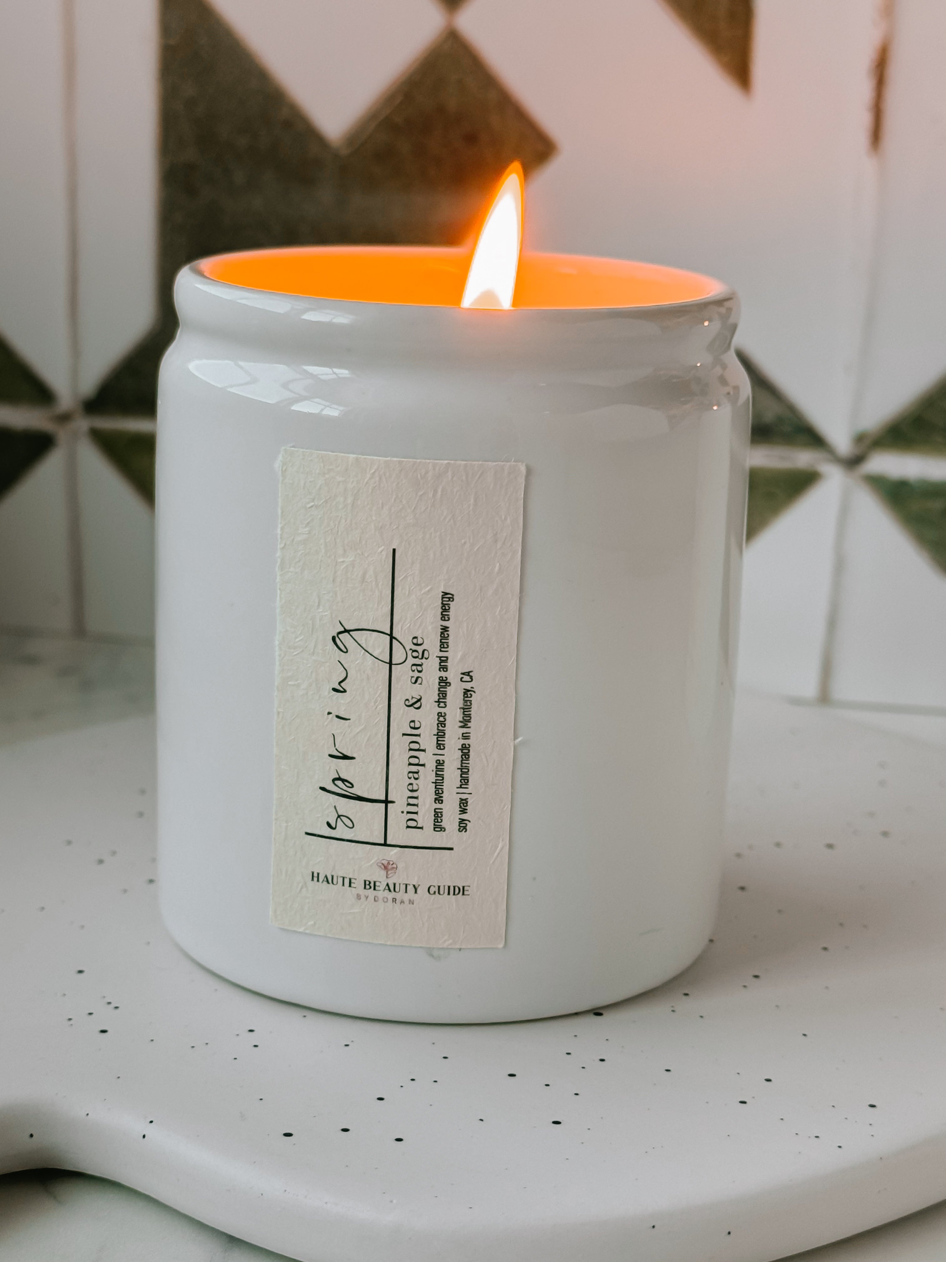 Spring Candle in a white jar with a label on a speckled surface