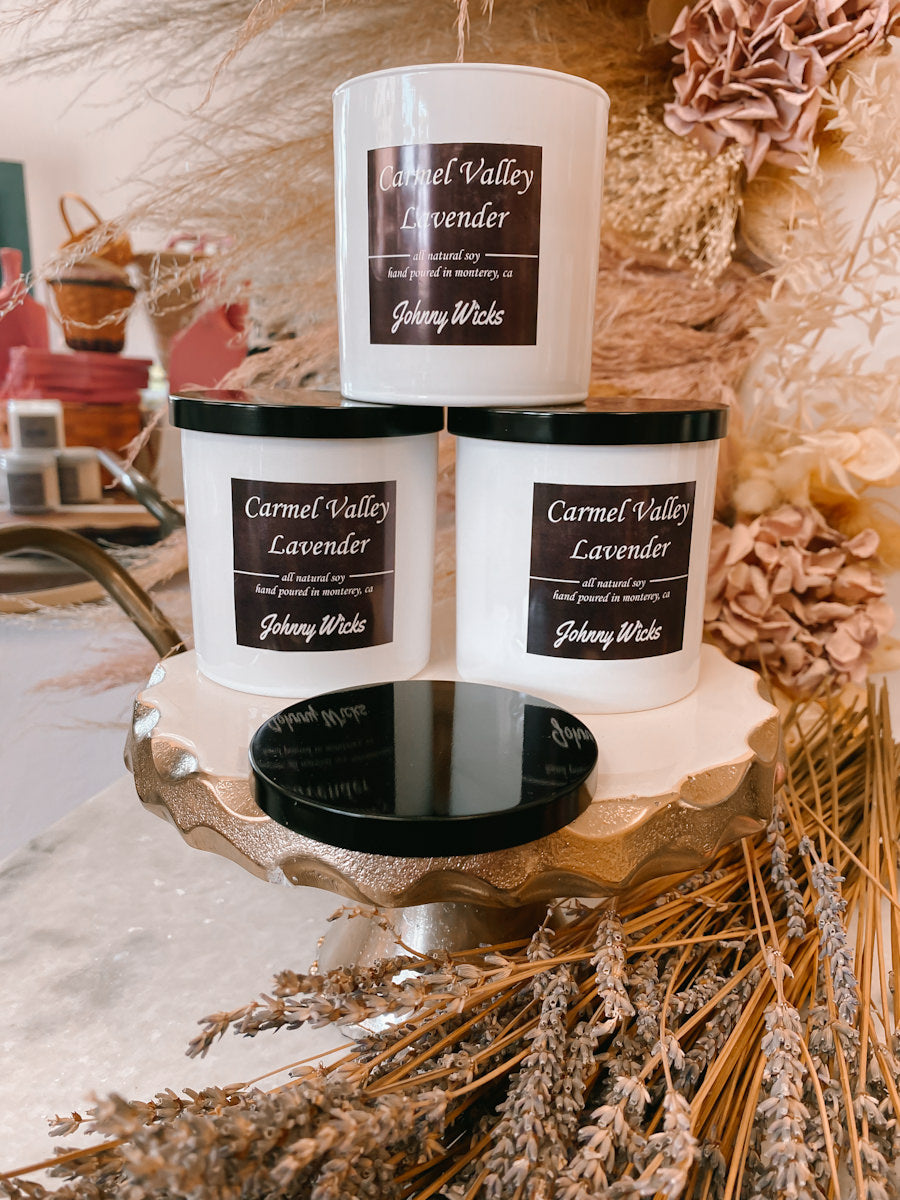 Three Johnny Wicks Carmel Valley Lavender candles on a decorative stand with dried lavender and flowers.