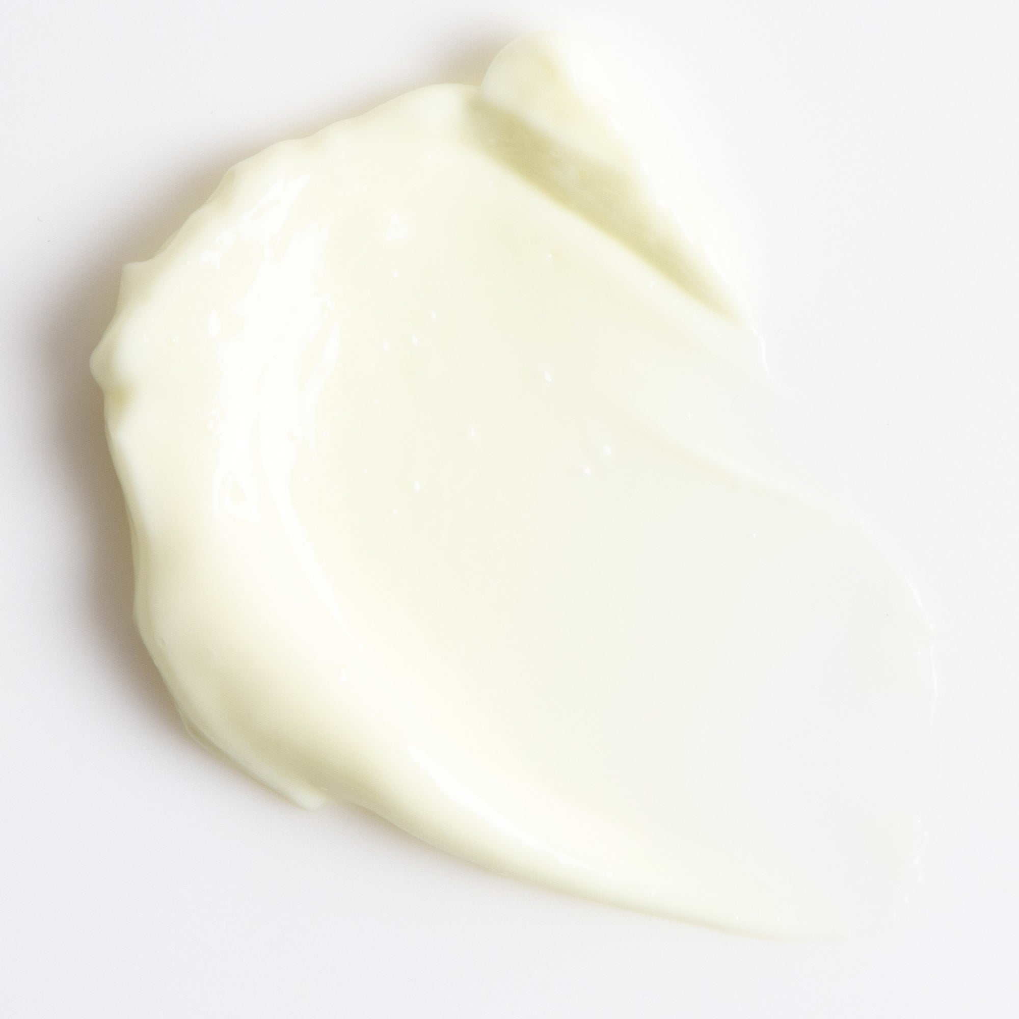 Close-up of a smooth, light-colored cream on a white background. Retinol plus close up smear. 