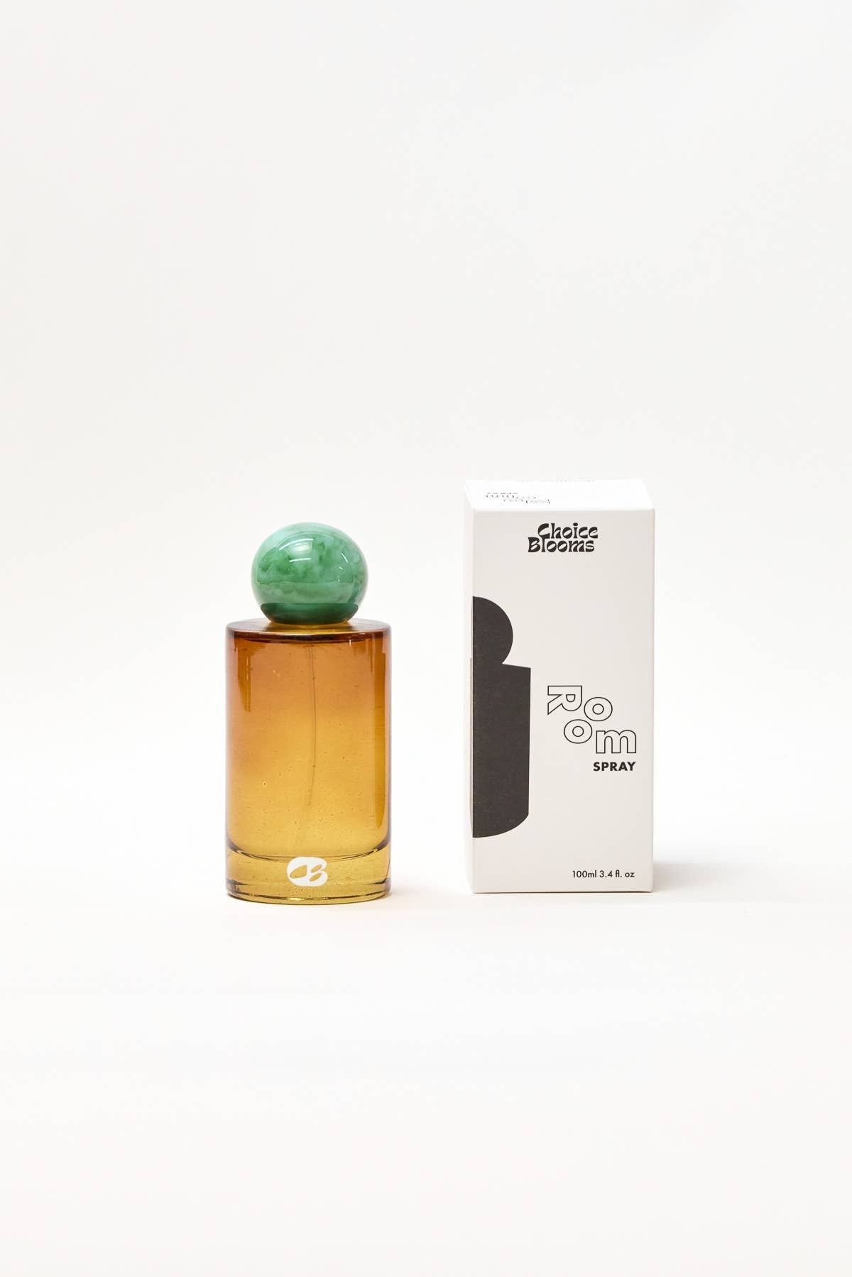 Perfume bottle with green cap and amber base next to its packaging on a white background